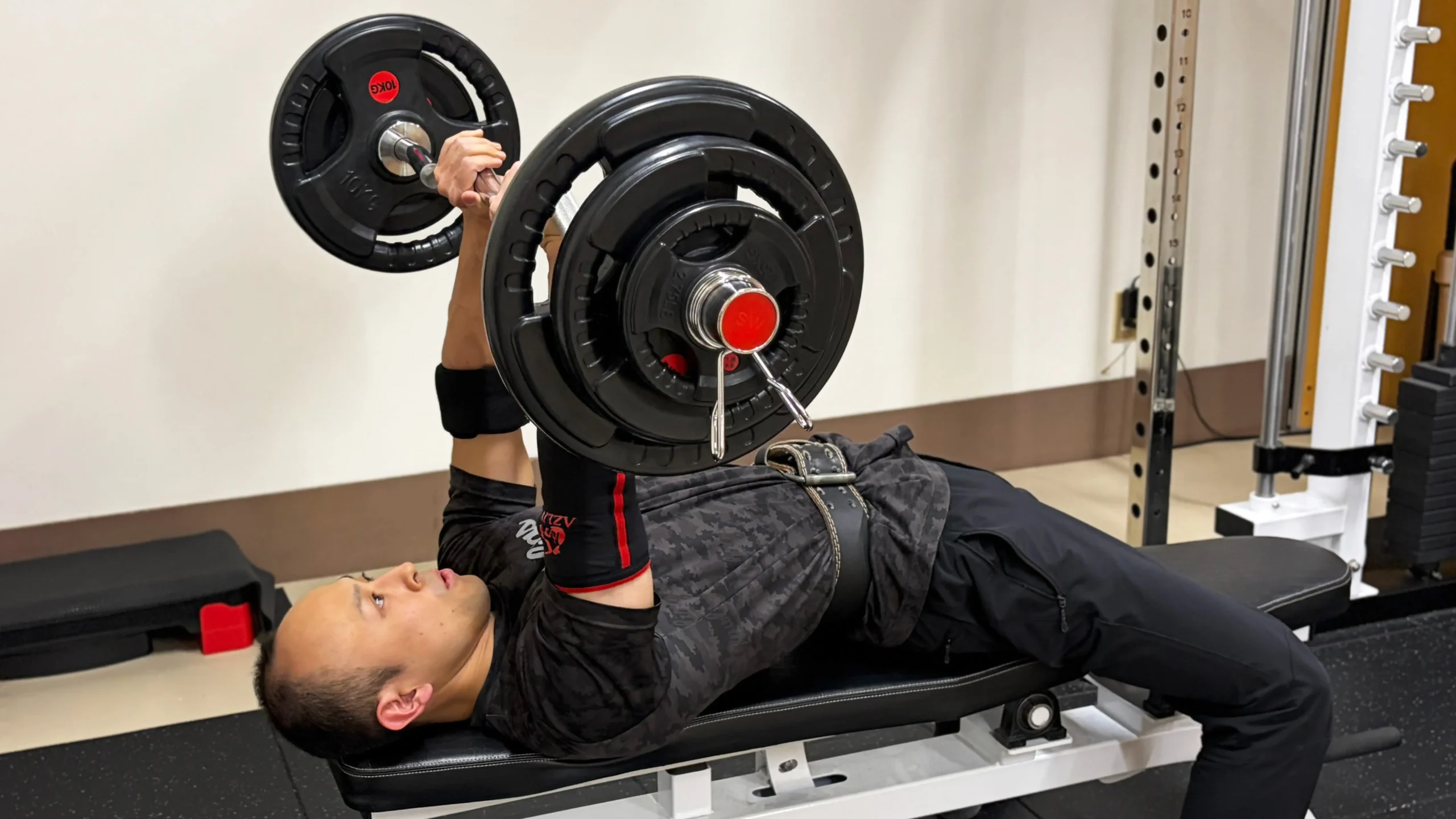 重たいダンベルでレッグカールをしている男性